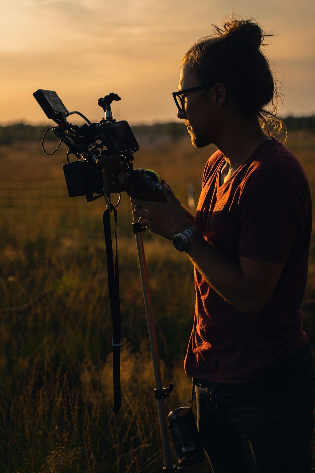 Reporter working outdoors with a camera rig at sunset