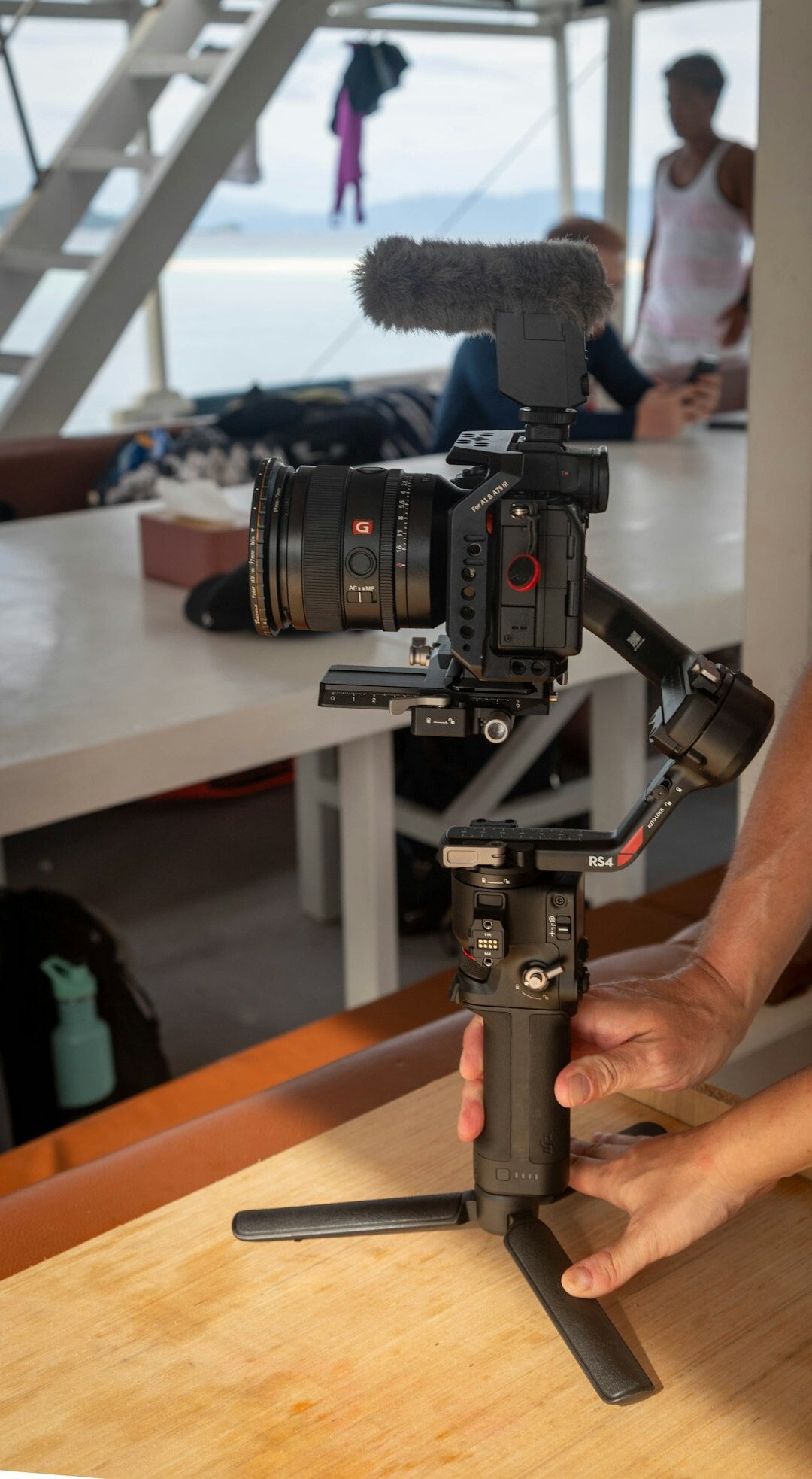 Hands operating a compact camera on a small gimbal stabilizer